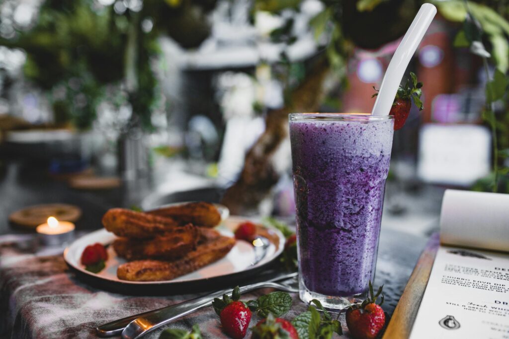 Delicious churros with fresh strawberries and blueberry smoothie in cafe